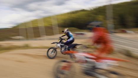 Three-motocross-riders-race-against-eachother-over-the-top-of-a-hill