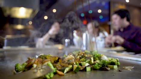 Slow-motion-of-sauce-being-added-to-vegetables-on-hot-plate,-hibachi-restaurant