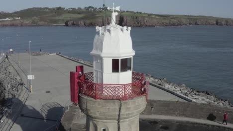 Orbiting-aerial-of-lighthouse-in-sunny-Dunmore-East-fishing-harbour