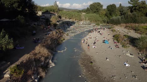 -SHOT:-empty-descriptive-front
-DESCRIPTION:-drone-video-over-the-thermal-baths-of-Saturnia,-Italy,-people-are-seen-bathing