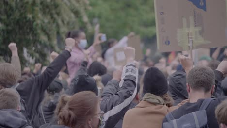 Crowd-of-protester-protesting-and-holding-signs-against-racism-while-clapping-and-raising-fists-at-a-black-lives-matter-protest-in-Stuttgart,-Germany