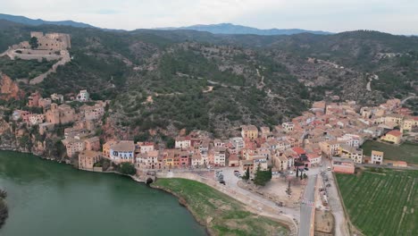 Miravet-town-in-tarragona,-spain,-surrounded-by-mountains-and-a-river,-daytime,-aerial-view