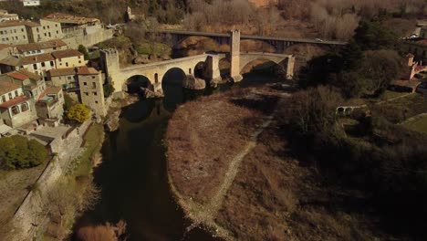 Besalu-town-in-girona-spain-with-a-medieval-bridge-over-a-river-during-daytime,-aerial-view
