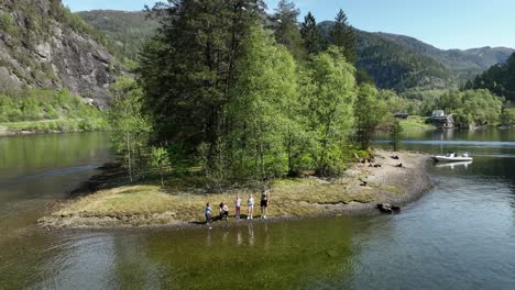 Zwei-Frauen,-Zwei-Mädchen-Und-Ein-Junge-Stehen-Am-Strand-Einer-Insel-Mit-Einem-Schlauchboot-Im-Hintergrund,-Luftaufnahme