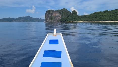 Bow-of-Boat-Sailing-in-Front-of-Uninhabited-Tropical-Island-and-Beach