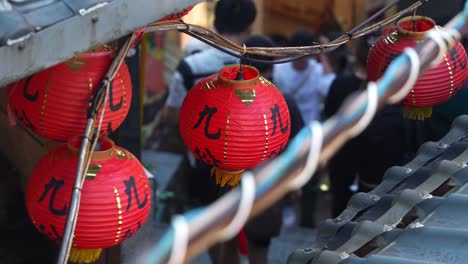 Traditional-red-lanterns-hanging-on-the-edge-of-the-roof-in-the-narrow-laneway-of-Jiufen-Old-Street,-a-charming-Taiwan-mountain-village-with-food-stalls,-souvenir-shops,-and-quaint-gift-boutiques