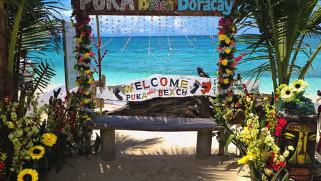 Welcome-to-Puka-Beach,-Boracay-Sign-and-Photography-Spot-in-Front-of-White-Sand-and-Turquoise-Sea