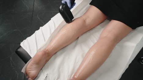 Laser-hair-removal-on-a-woman's-legs,-with-a-gloved-technician-applying-the-treatment