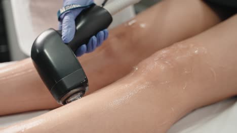 Close-up-of-laser-hair-removal-on-a-woman's-lower-leg,-technician-using-a-handheld-device