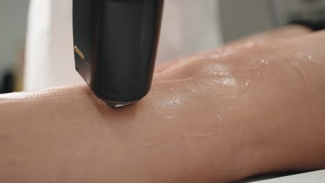 Close-up-view-of-laser-hair-removal-on-a-woman's-leg,-technician-applying-the-treatment