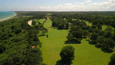 An-drone-flight-over-the-Normandy-American-Cemetery-and-Memorial,-with-rows-of-white-crosses-marking-graves-of-US-soldiers-fallen-during-the-Normandy-invasion-at-Omaha-and-Utah-Beach-on-D-Day,-1944