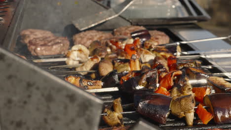 Chef-Flipping-Hamburgers-on-BBQ-with-Vegetable-Shish-Kebabs-with-Flames-and-Smoke