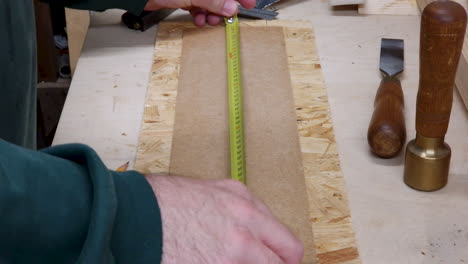 A-joiner-marks-a-workpiece-using-a-tape-measure-and-pencil