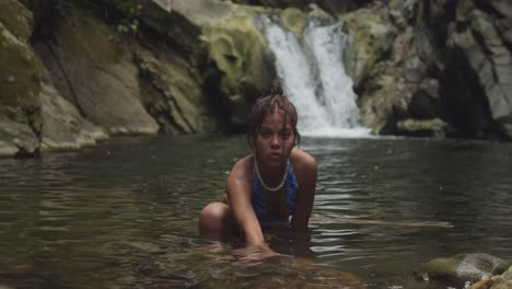 On-Trinidad's-island,-a-bikini-clad-young-girl-enjoys-the-waterfall-and-river