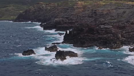 Wide-aerial-establishing-shot-of-rocky-coast-of-Maui-with-rough-seas-and-waves-crashing-on-the-rocks