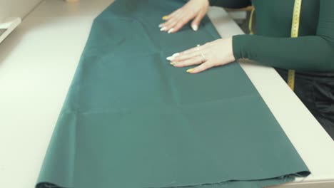 Female-seamstress-tailor-unfolding-green-fabric