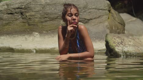 On-the-tropical-island-of-Trinidad,-a-young-girl-in-a-bikini-enjoys-the-waterfall-and-river