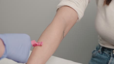 Technician-preparing-a-woman's-arm-for-laser-hair-removal-with-a-pink-clip-and-gloves