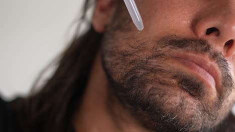 man-applying-minoxidil-to-his-beard-with-a-dropper,-scalp