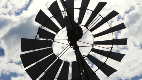 Close-up-views-of-a-windmill-in-full-operation-contrasting-with-the-blue-sky-and-clouds