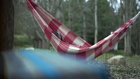 A-person-resting-in-a-red-hammock-at-an-outdoor-campsite