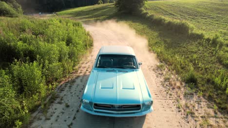 An-old-Ford-Mustang-67,-is-driving-on-a-gravel-road,-aerial-view