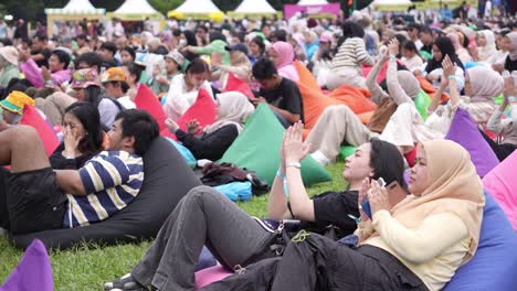 Indonesian-People-At-Outdoor-Festival-Lying-On-Bean-Bags-On-Lawn-Applauding-Clapping