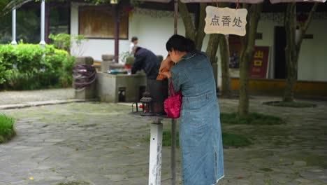 Chinese-woman-lighting-incense-sticks-at-temple-courtyard