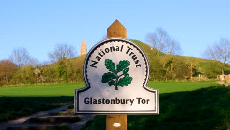 National-Trust-signpost-at-the-foot-of-Glastonbury-Tor-in-rural-countryside-of-the-Somerset-Levels-in-England-UK
