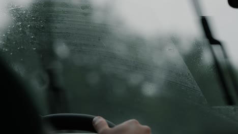 Raindrops-on-windshield-with-blurred-highway-driving-scene