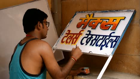 a-painter-painting-shop-name-outside-his-house-on-a-board