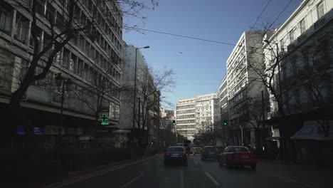 car-ride-at-Athens-city-centre-in-Greece-,-people-walking-,light-traffic-at-road-greek-architecture-,-heart-of-city-urban-lifestyle-summer-sunny-day