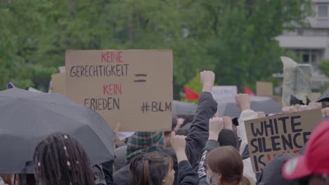 Crowd-of-protester-protesting-and-holding-signs-against-racism-while-cheering-and-raising-fists-at-a-black-lives-matter-protest-in-Stuttgart,-Germany