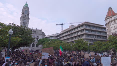 Porto---Portugal---june-6th-2020:-BLM-Black-Lives-Matter-Protests-Demonstration-with-protesters-holding-black-lives-matter-signs-in-the-air-and-city-hall-in-the-background-and-portuguese-flag