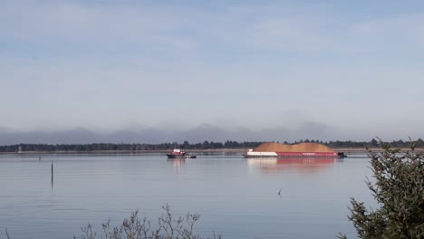 A-ship-pulling-a-large-barge-full-of-wood-chips