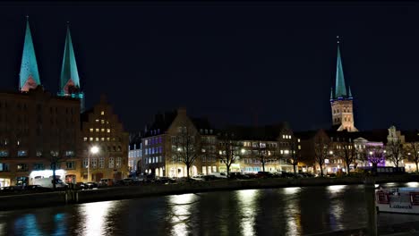 Time-lapse-of-churches-at-Lübeck,-Germany,-across-a-canal-at-night