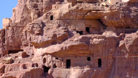 Close-up-view-of-houses,-windows-and-doorways-carved-into-the-red-sandstone-mountains-in-the-ancient-city-of-Petra-in-Jordan