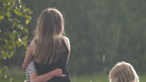 Happy-kids-hugging-each-other-in-the-garden-while-raining