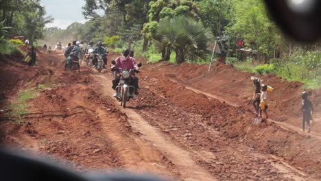 Village-People-Walking-And-Riding-Motorcycles-In-Rural-Uganda,-Africa