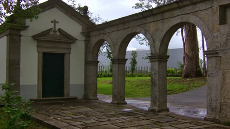 Static-shot-of-a-little-christian-chapel-in-a-park-with-some-stone-arches-by,-in-Porto