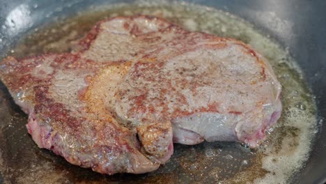 Entrecote-steak-in-pan,-raw-red-top-turned-to-sear,-browned-side-visible-after-turning,-closeup,-60-fps
