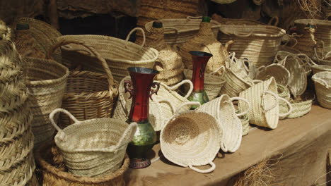 Amazing-shot-of-a-group-of-handmade-baskets-made-with-yellow-straw-at-a-stand-inside-a-medieval-fair-in-Andalusia,-Spain