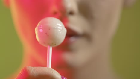 Rack-focus,-close-up-young-female-blue-tongue-licks-a-white-sweet-lollipop