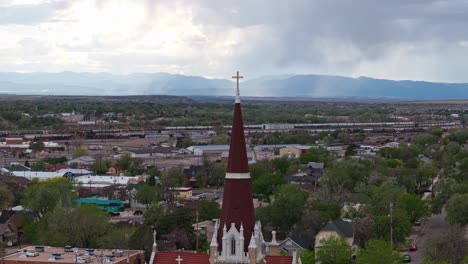 Drone-parallax-above-gothic-revival-spire-with-cross-over-Pueblo-Colorado