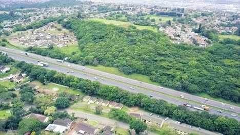 Aerial-footage-of-a-drone-flying-over-residential-houses-overlooking-a-busy-highway-with-moving-traffic-in-a-suburb-of-yellow-wood-park-Durban