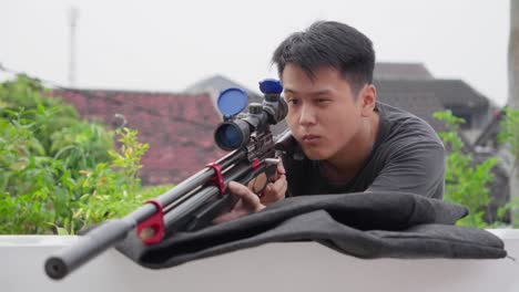 Asian-sniper-flips-up-lens-cap-covers-on-scoped-pcp-air-rifle-looking-and-aiming