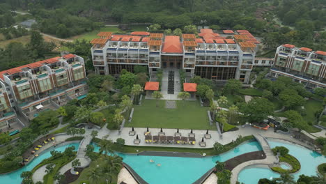 Drone-Descend-Over-Holiday-Resort-Lawn-And-Pool-Area-Chan-May-Bay-Lang-Co-Vietnam-60-FPS
