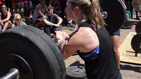 A-fit-young-women-squatting-using-an-olympic-barbell-during-a-cross-fit-competition,-strength-training-for-muscular-endurance,-healthy-and-good-for-weight-loss-and-muscular-and-core-developement