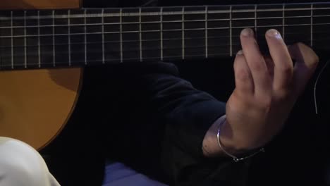 Flamenco-musician-playing-traditional-guitar,-dark-room