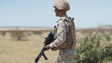 SLOW-MOTION:-A-US-Marine-positioned-in-the-desert-runs-through-the-brush-and-sand-with-rifle-in-hand